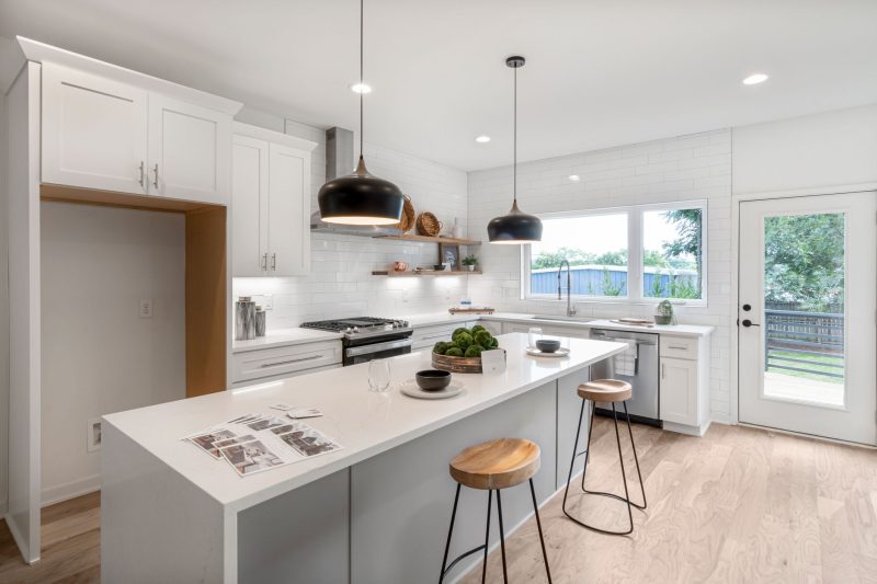 Bright modern kitchen with white cabinetry wooden stools and 1792515725